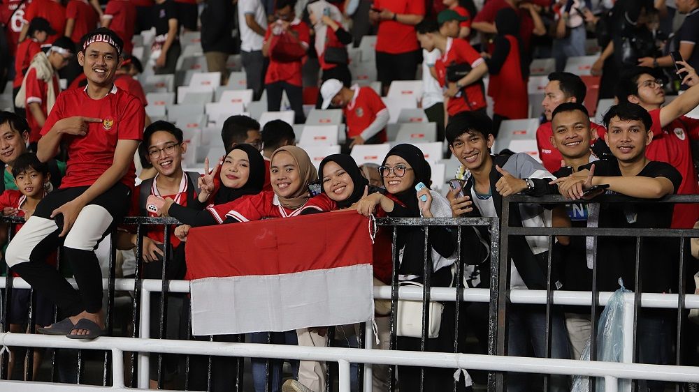 Suporter Timnas Indonesia berpose sambil membentangkan bendera merah-putih dalam laga melawan Vietnam pada Kualifikasi Piala Dunia 2026 Zona Asia di SUGBK, Jakarta, 21 Maret 2024. (Mario Sonatha untuk Skor.id)