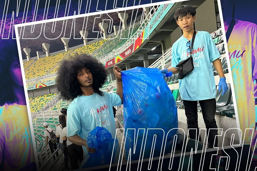 Ikram Afro dengan suporter lainnya bersihkan sampah di stadion. (Dok. LOC WCU17/Grafis Yusuf/Skor.id).