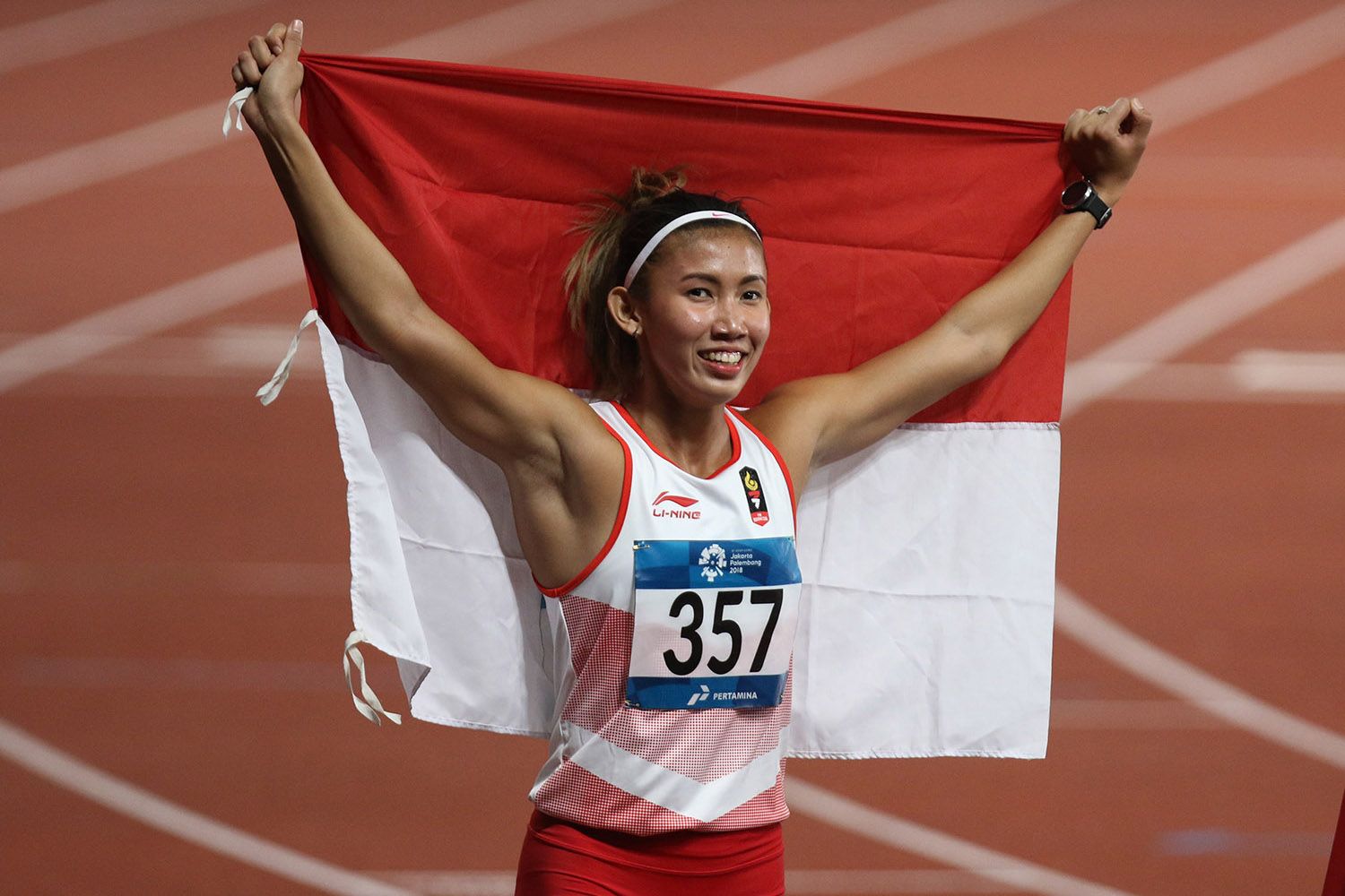Emilia Nova membentangkan bendera Merah-Putih usai meraih perak lari gawang 100 meter putri Asian Games 2018.