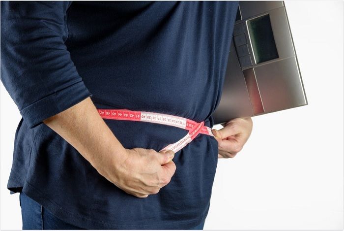 Ilustrasi seseorang dengan pita pengukur dan timbangan badan.