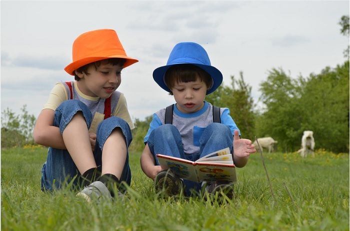 Ilustrasi dua anak kecil sedang membaca buku. Mereka bisa mendapatkan informasi soal perang di Ukraina dari banyak cara.