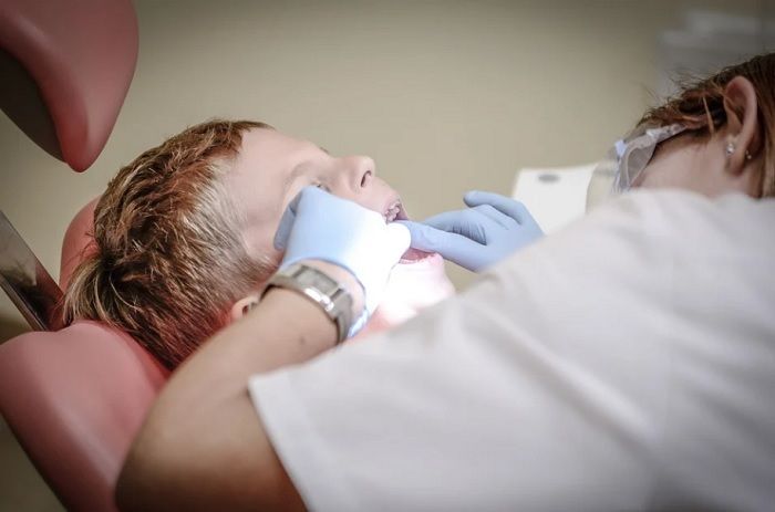 Ilustrasi dokter sedang melakukan pemeriksaan gigi pada seorang anak.