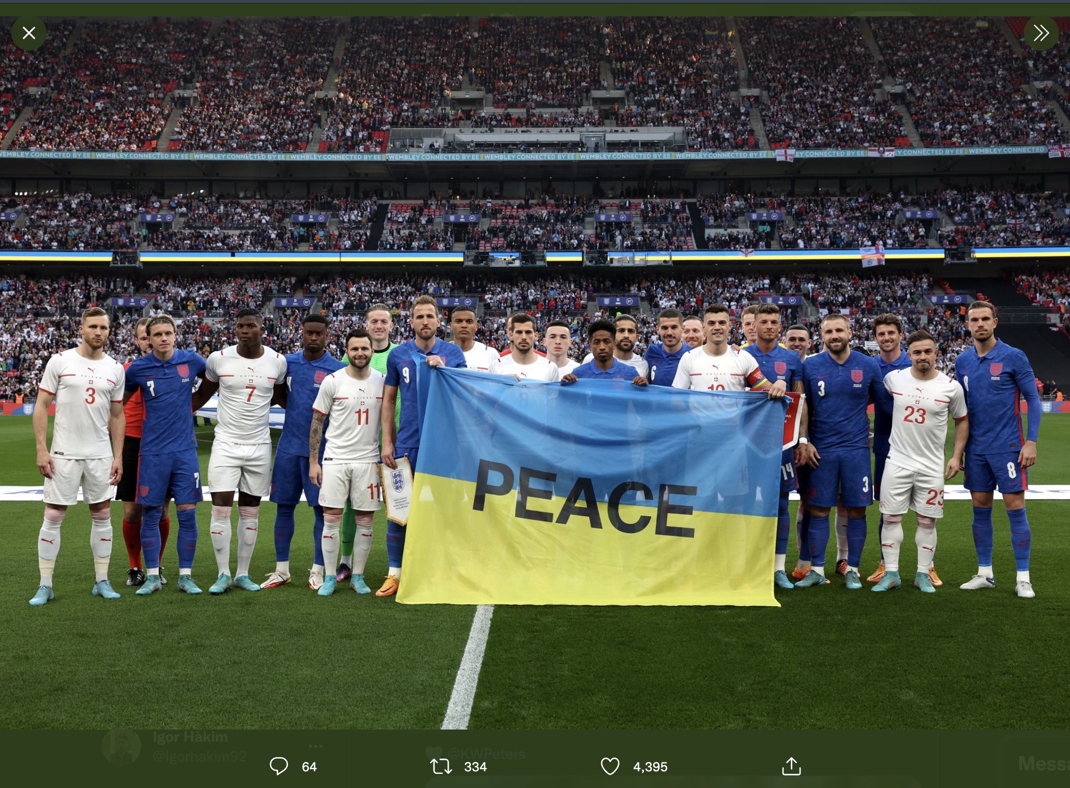 Para pemain Inggris dan Swiss saat membentangkan bendera Ukraina bertuliskan 'Peace' alias 'Damai'.