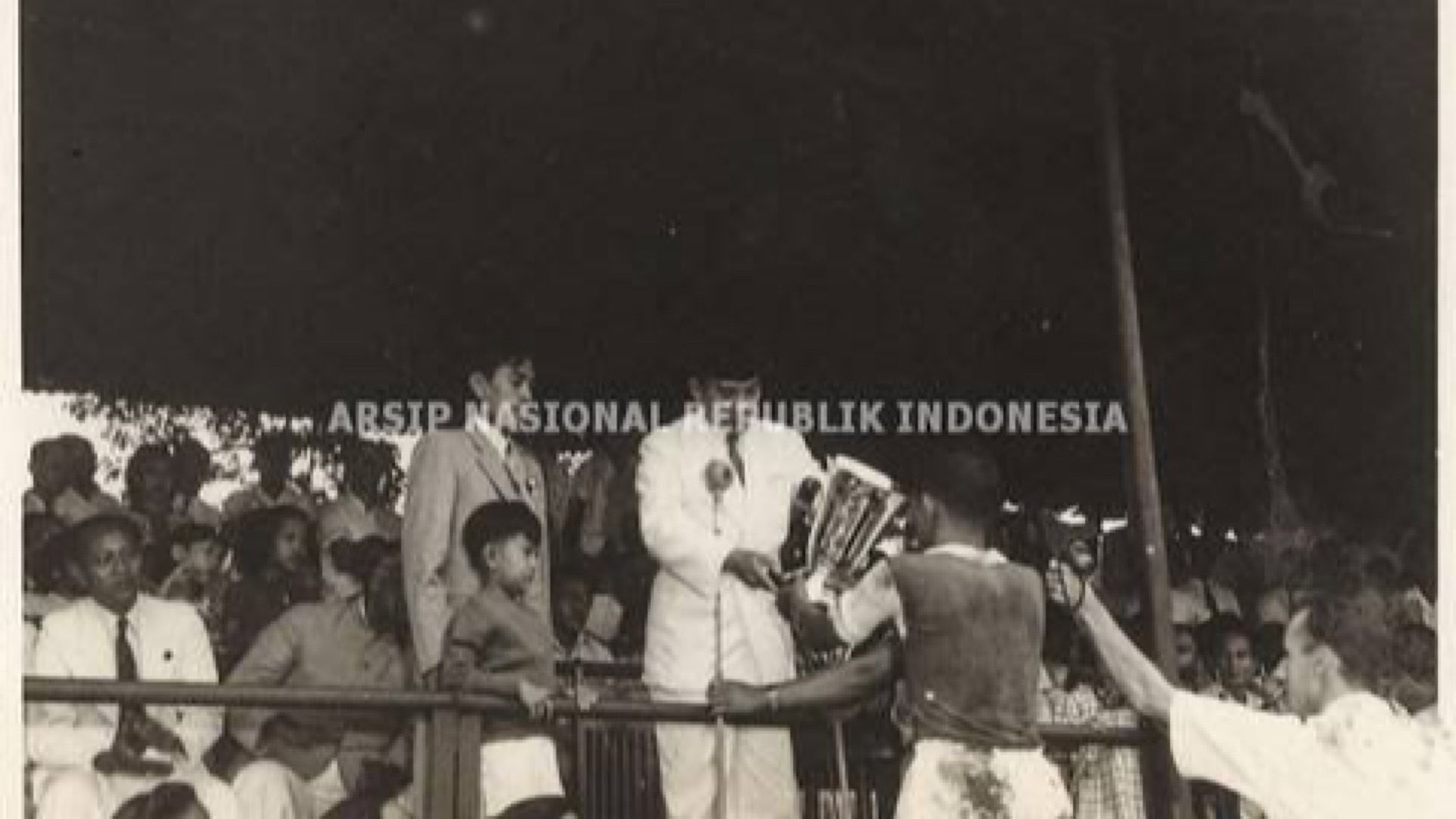Presiden Soekarno memberikan piala kepada seorang pemain yang menjuarai pertandingan sepak bola di Lapangan Bataviase Voetbal Club (BVC).
