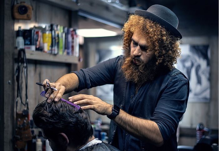 Ilustrasi seorang tukang cukur rambut sedang melayani seorang pelanggan.