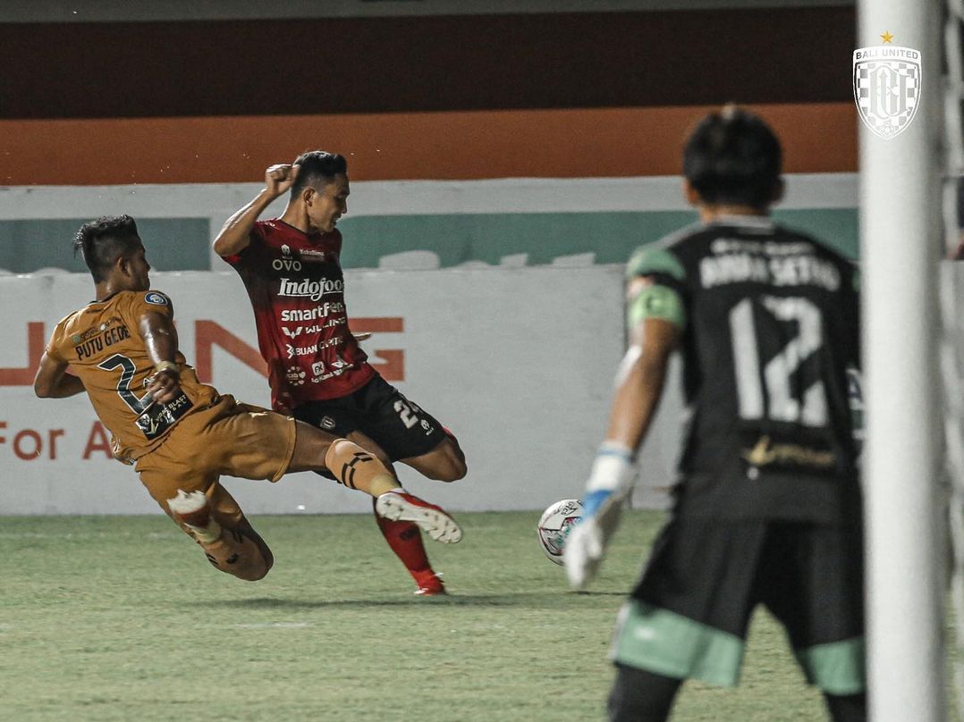Bek Bhayangkara FC, Putu Gede melakukan takel untuk menghalau serangan Bali United.