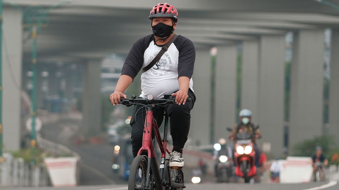 Aktivitas bersepeda di jalan raya yang aman dengan memakai helm yang sesuai kebutuhan.