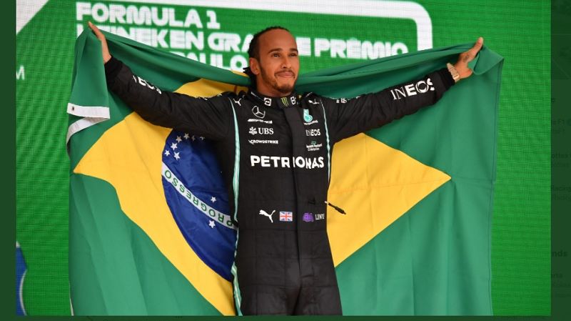 Pembalap Mercedes-AMG Petronas, Lewis Hamilton, berpose dengan membentangkan bendera Brasil saat memenangi F1 GP Sao Paulo 2021 yang berlangsung di Sirkuit Interlagos pada Senin (15/11/2021) dini hari.
