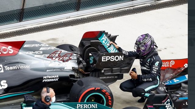 Lewis Hamilton berjongkok mengecek kondisi mobilnya setelah menjalani sesi kualifikasi F1 GP Rusia 2021 yang digelar di Sochi Autodrom pada Sabtu (25/9/2021).