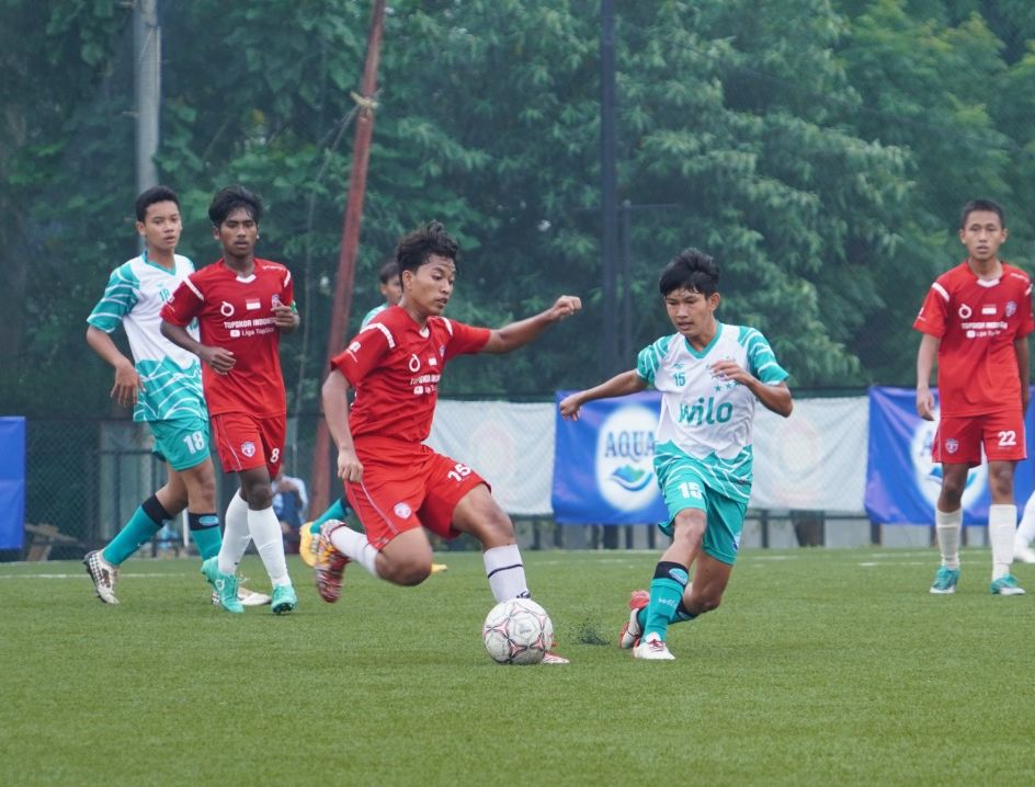 Pemain TSI Jakarta (merah) berusaha untuk melewati pemain Ocean Stars (putih) pada babak semifinal TopSkor Cup Nasional U-16 2022