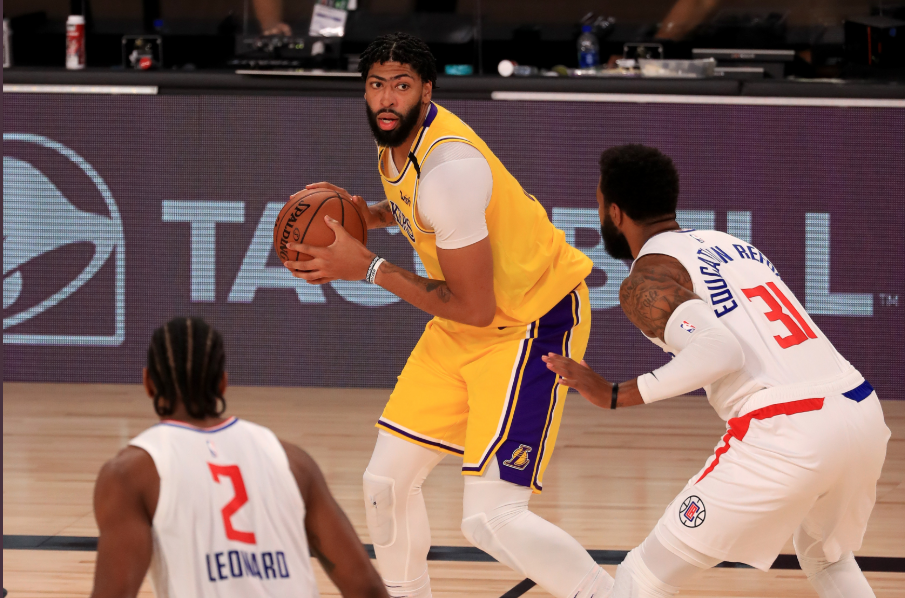 Forward LA Lakers, Anthony Davis, coba melewati penjagaan pemain LA Clippers, Kawhi Leonard (kiri) dan Marcus Morris Sr dalam lanjutan NBA 2019-2020 di The Arena, Orlando, Florida, Kamis (30/7/2020) malam. 